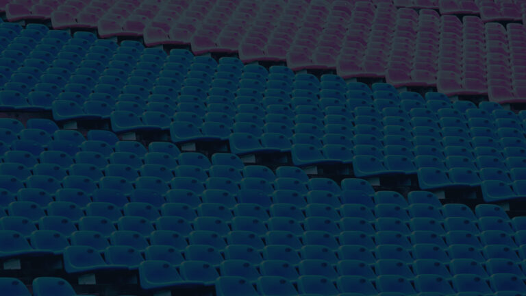 Leere Sitzreihen in einem Stadion in Blau- und Violetttönen aus erhöhter Perspektive.
